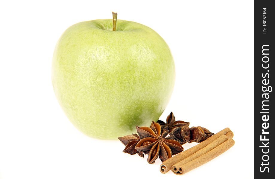 Delicious fresh green apple with anise stars and cinnamon sticks isolated on white.
