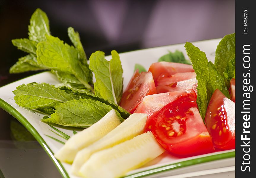 Dish of various vegetables such as tomatoes, cucumbers and mint