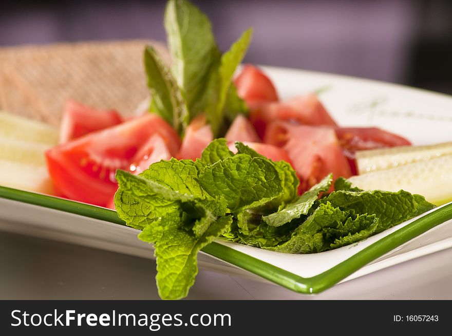 Dish of various vegetables such as tomatoes, cucumbers and mint