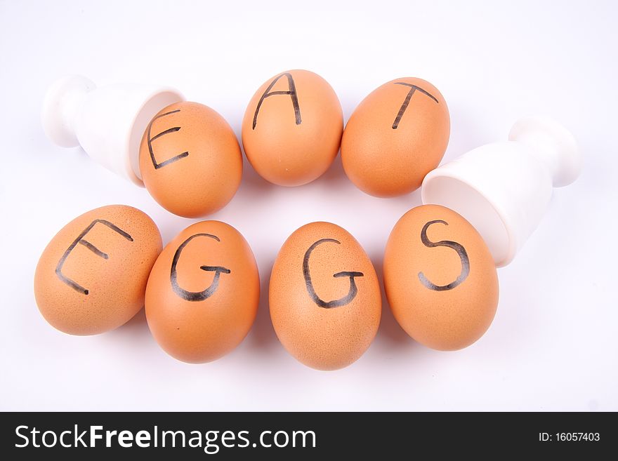 Eggs with an inscription EAT EGGS and egg holders on white background