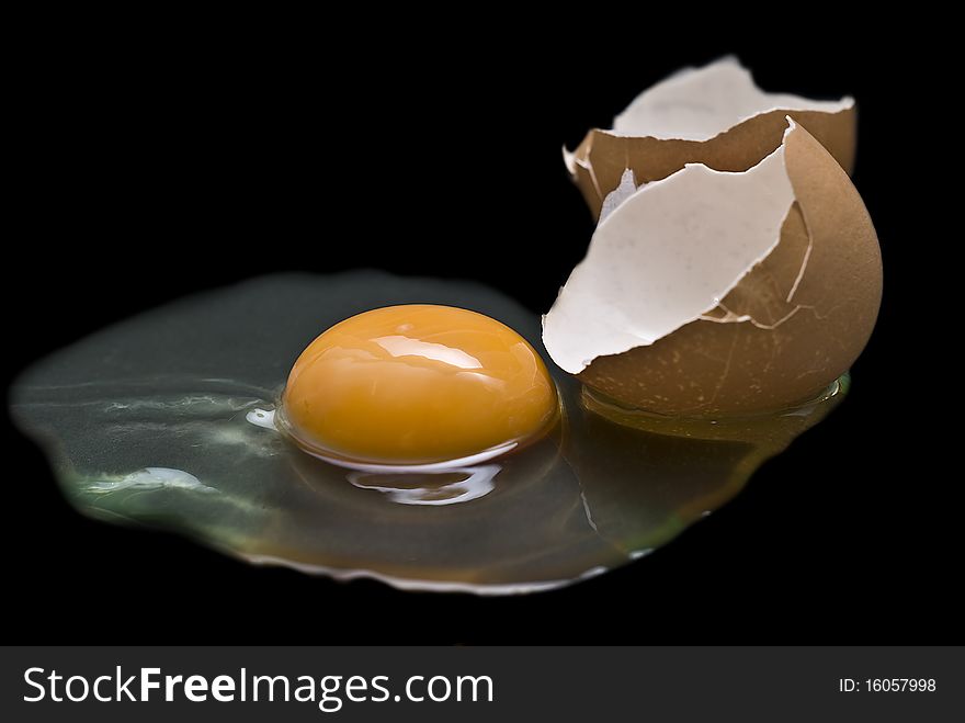 A cracked raw egg on a black background. A cracked raw egg on a black background.