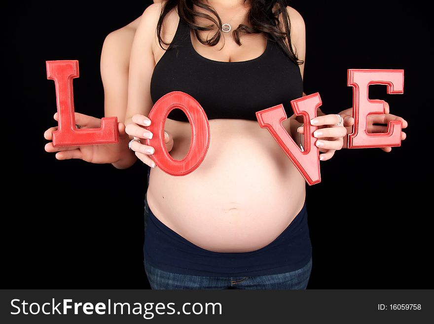 Woman and man hold the letter L O V E in front of pregnant womans stomach