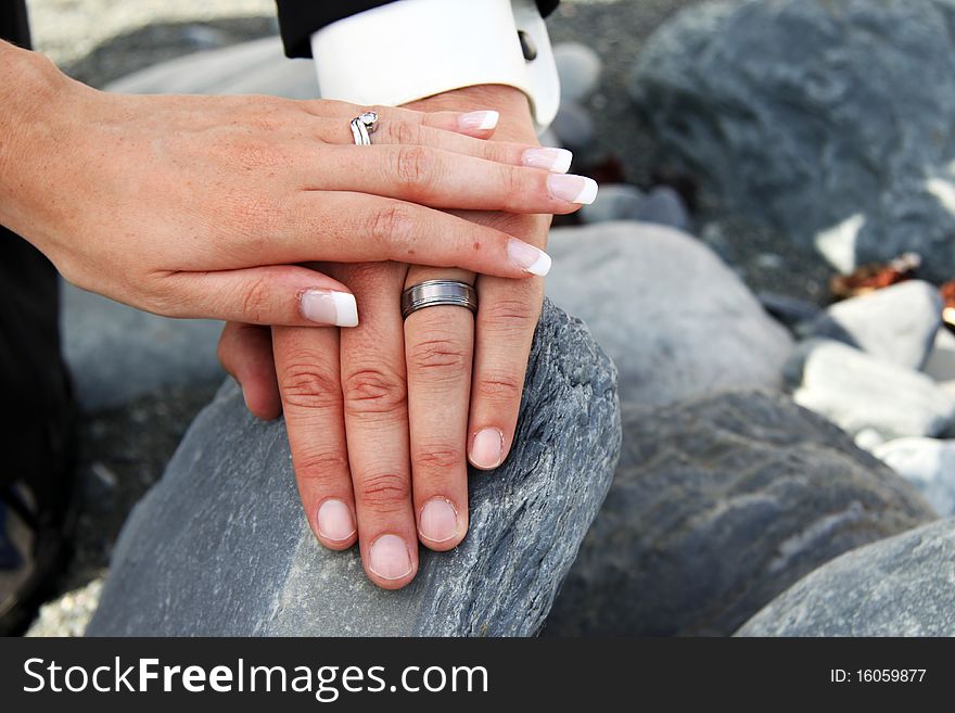 Married couple with hands on top on each other on a rock. Married couple with hands on top on each other on a rock