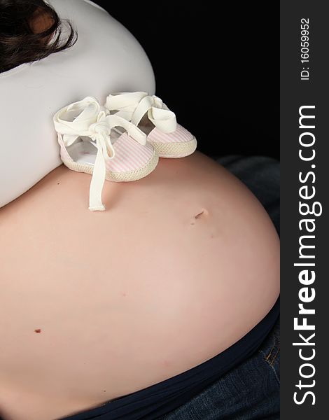 Pair of baby shoes on pregnant womans stomach. Pair of baby shoes on pregnant womans stomach