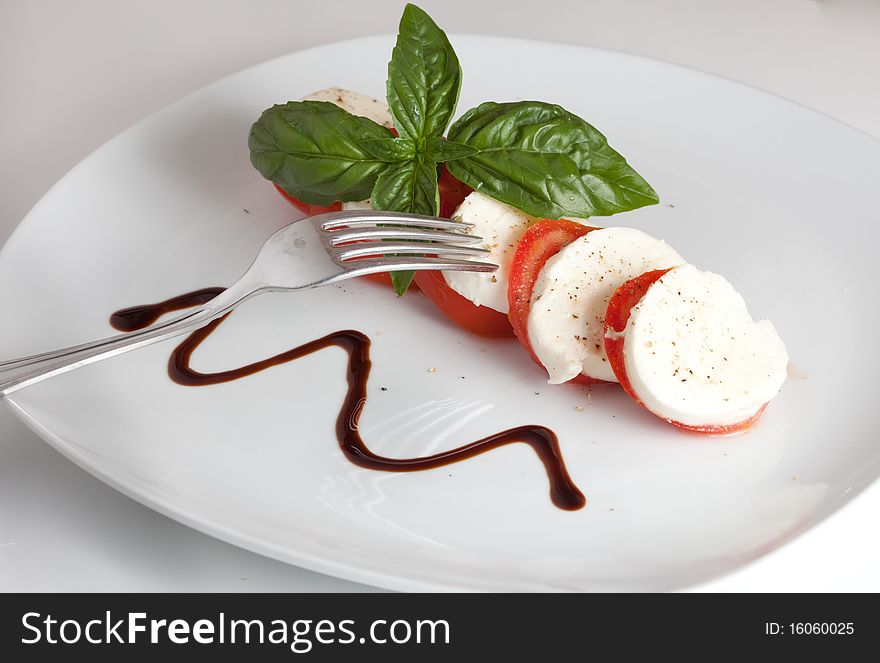 Italian caprese made of tomato, mozzarella and basil putted on a white isolated background. Italian caprese made of tomato, mozzarella and basil putted on a white isolated background