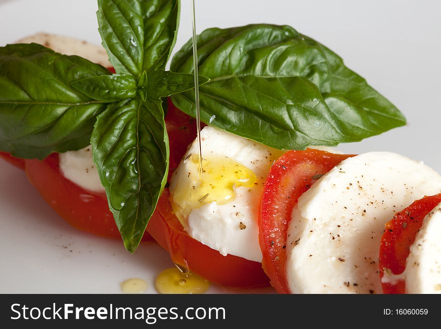 Italian caprese made of tomato, mozzarella and basil putted on a white isolated background. Italian caprese made of tomato, mozzarella and basil putted on a white isolated background