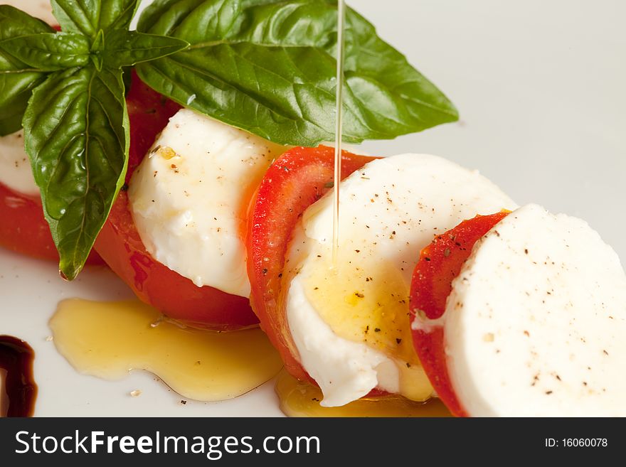 Italian caprese made of tomato, mozzarella and basil putted on a white isolated background. Italian caprese made of tomato, mozzarella and basil putted on a white isolated background