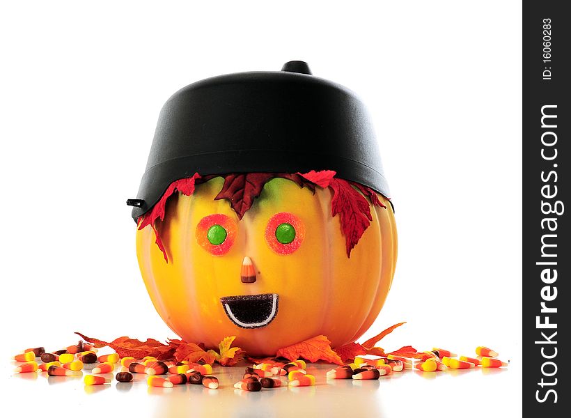 A pumpkin head with a cauldron hat, leaf hair and halloween candy face, surrounded by spilled candy corn.. Isolated on white. A pumpkin head with a cauldron hat, leaf hair and halloween candy face, surrounded by spilled candy corn.. Isolated on white.