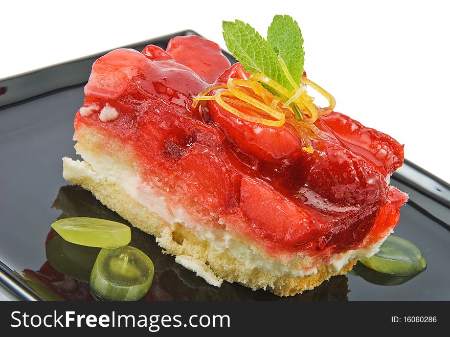 Cheesecake with strawberries on black plate isolated. Cheesecake with strawberries on black plate isolated