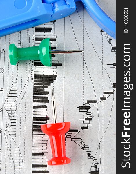 Blue magnifier and drawing pin in red and green color, putting on a stock graph, means business and finance analysis and key point. Blue magnifier and drawing pin in red and green color, putting on a stock graph, means business and finance analysis and key point.