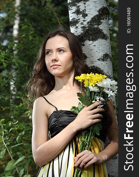 Girl with a flower bunch near a birch. Girl with a flower bunch near a birch