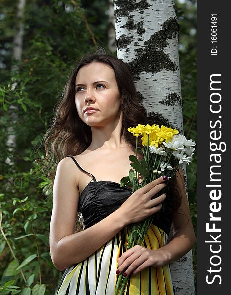 Girl with a flower bunch near a birch. Girl with a flower bunch near a birch