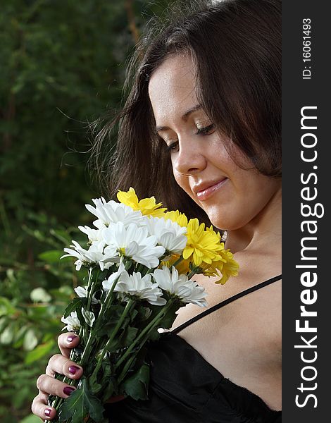 Girl with a flower bunch near a birch loock to the flowers. Girl with a flower bunch near a birch loock to the flowers