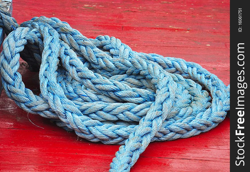Blue rope coiled on the deck of an old red boat. Blue rope coiled on the deck of an old red boat