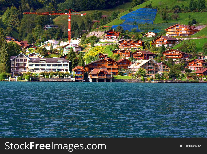 A old Swiss Village next to a lake near Interlachen on a green hill with trees in Switzerland