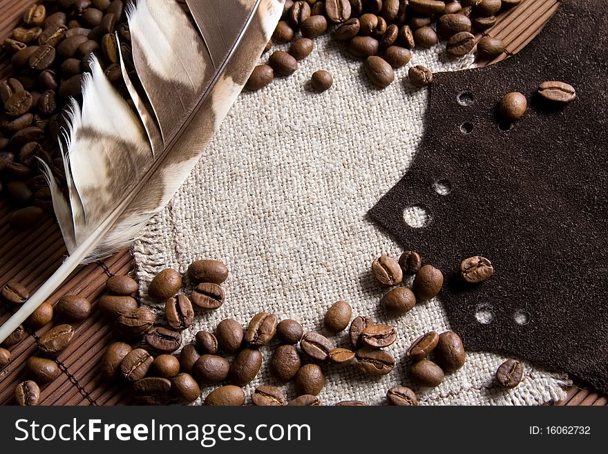 Coffee beans background with brown leather and bird feather
