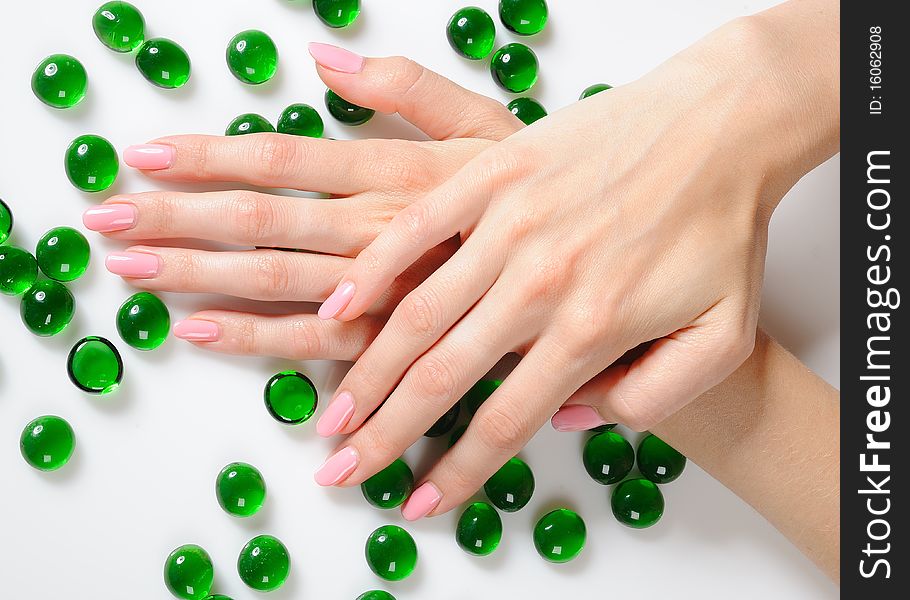 Beautiful hands with perfect nail pink manicure and green decorative stones. isolated on white background