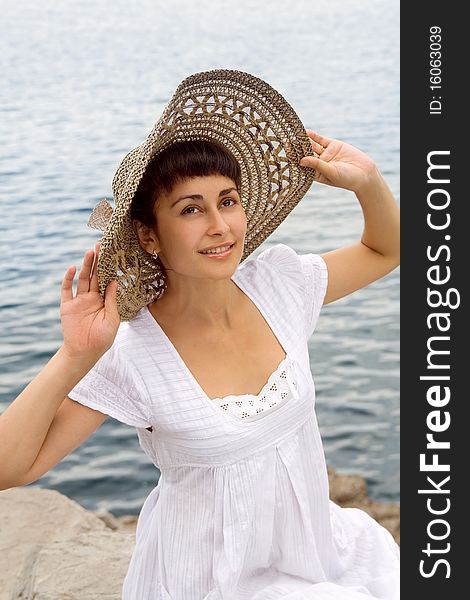 Happy young girl in the bonnet near the sea