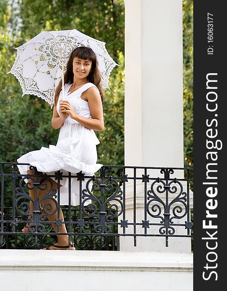 Young attractive girl with white  sun umbrella sitting in the park. Young attractive girl with white  sun umbrella sitting in the park