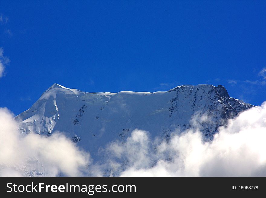 Top of a mountain covered in snow rising above the clouds like mount olympus. Top of a mountain covered in snow rising above the clouds like mount olympus