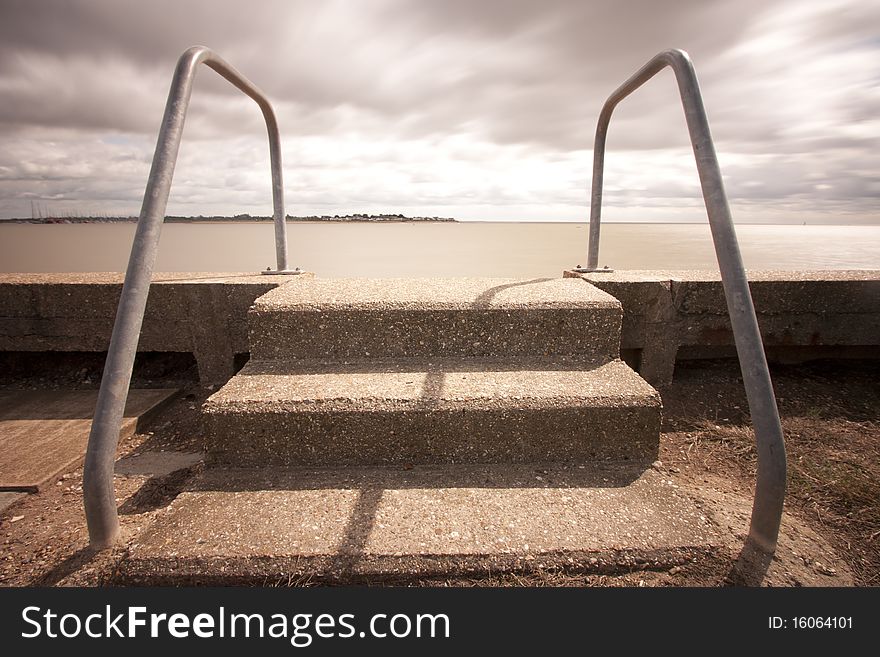 Concrete steps lead down into murky water in essex. Concrete steps lead down into murky water in essex