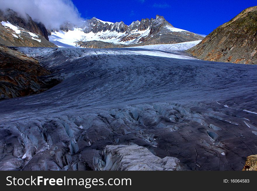 A Glacier leading down from a snow capped mountain under a sunny blue sky with clouds. A Glacier leading down from a snow capped mountain under a sunny blue sky with clouds