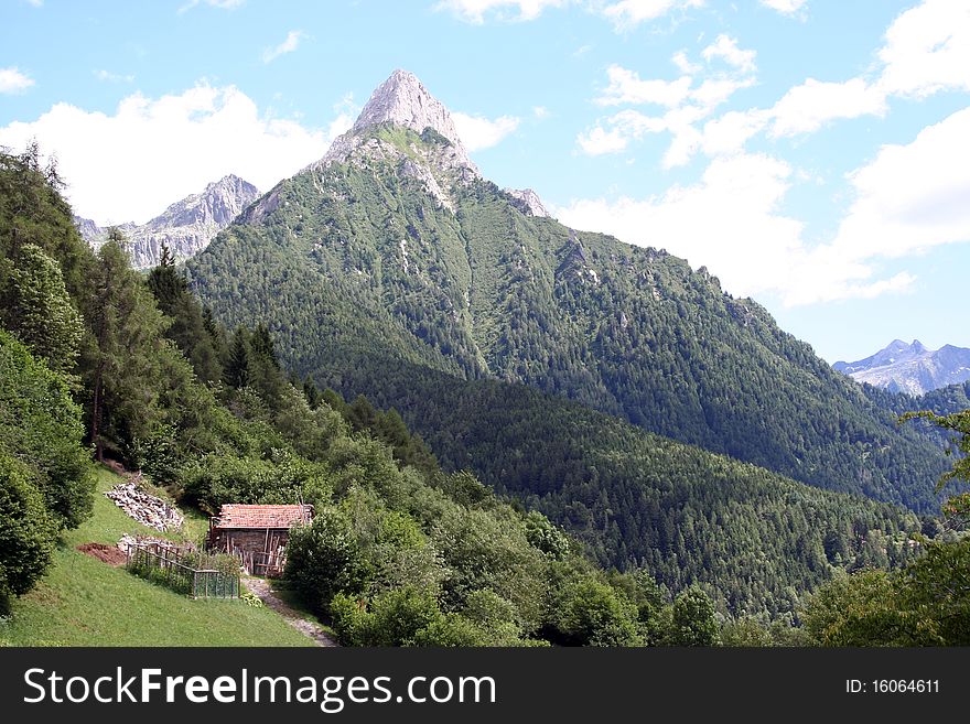 Mountain horizontal landscape with a small wooden house in northern Italy in summer. Mountain horizontal landscape with a small wooden house in northern Italy in summer