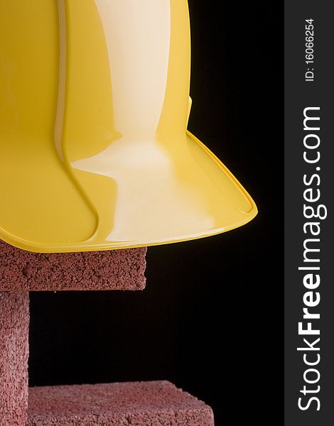 Yellow hard hat and red bricks on a black background.