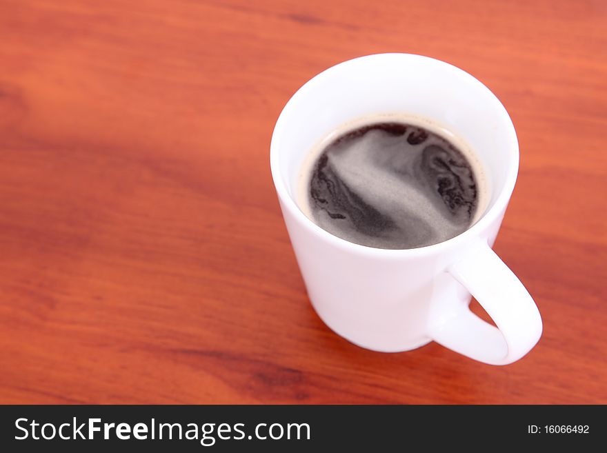 White cup with coffee on wooden desk. White cup with coffee on wooden desk