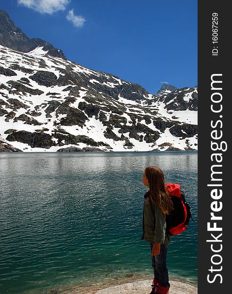 Little girl tourist in Hight mountain lake looking at beautiful landscape of Artouste lake in spring time