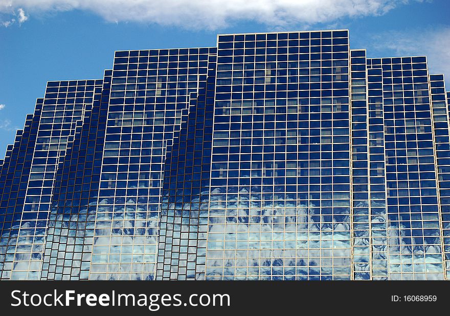 View of glass building with mirrored windows reflecting the sky. View of glass building with mirrored windows reflecting the sky.