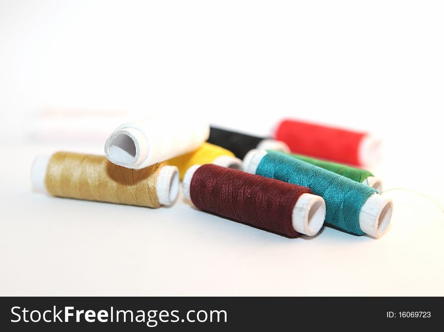 Nine reels of colored thread on a white background. Nine reels of colored thread on a white background