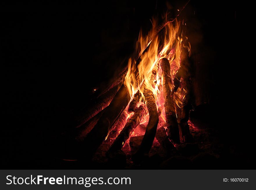 Campfire burning with logs, late at night.