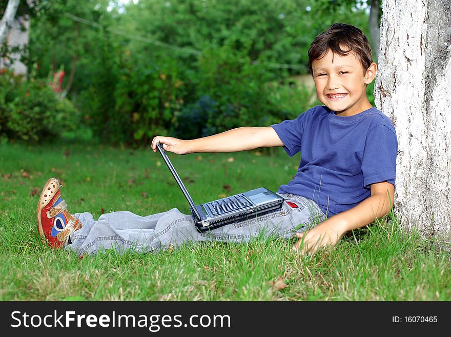 Boy with notebook sit at tree outdoors