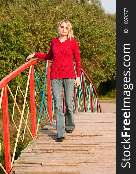 A girl in red pullover walking on a bridge