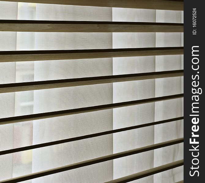 a close up of wooden blinds with net curtains behind them. a close up of wooden blinds with net curtains behind them