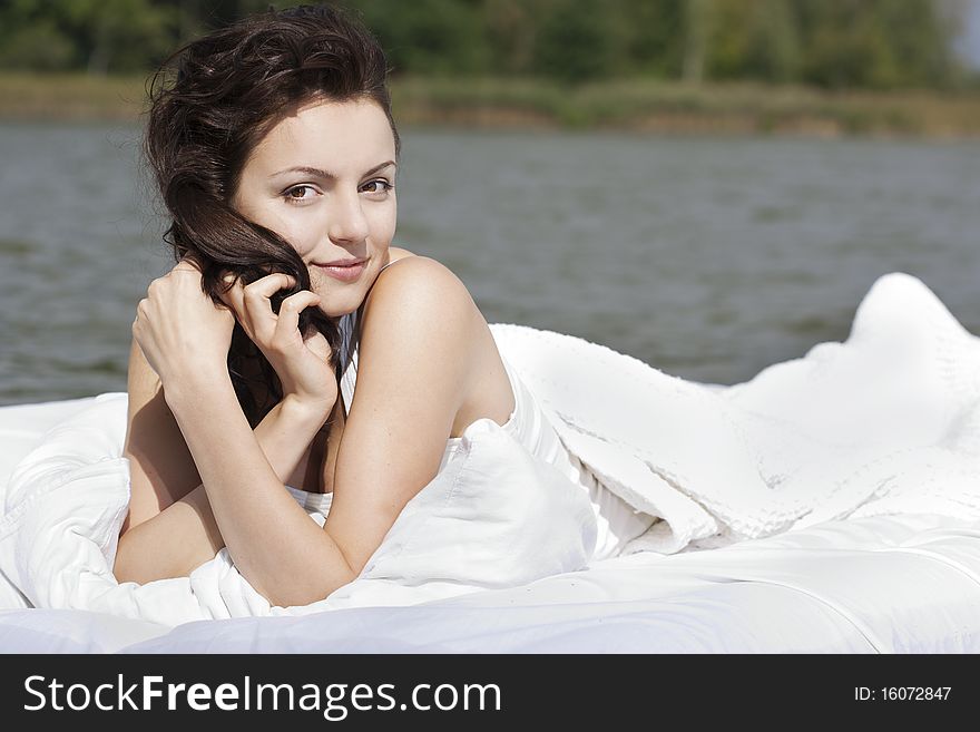 Beautiful young woman lying on the white bed in the sea. Beautiful young woman lying on the white bed in the sea