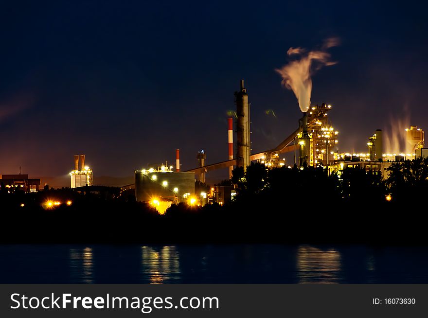 Industrial buildings in the evening. twilight. foreground is a river. background the sky. Industrial buildings in the evening. twilight. foreground is a river. background the sky