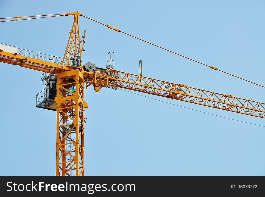 Closeup of yellow jib crane against blue sky. Closeup of yellow jib crane against blue sky