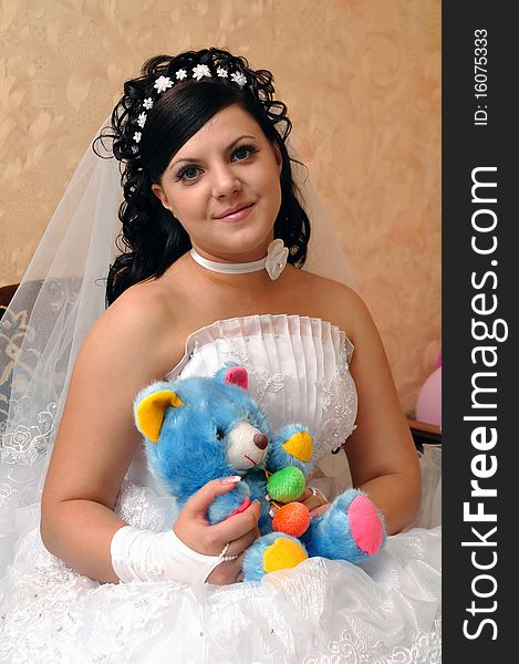 The bride sits on a sofa and toy bear holds in hands. The bride sits on a sofa and toy bear holds in hands