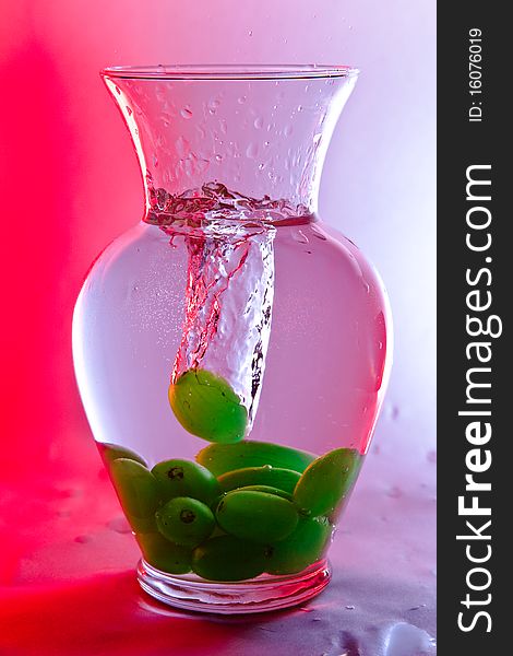 Single grape drops in a vase full of water and submerged grapes. Single grape drops in a vase full of water and submerged grapes