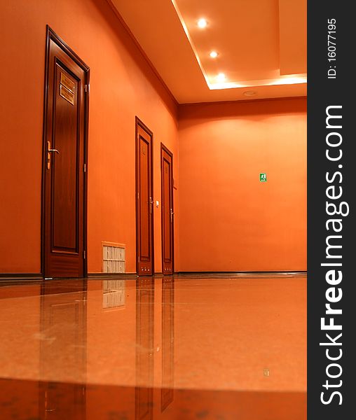 Three doors in an empty corridor, walls and a ceiling of orange color