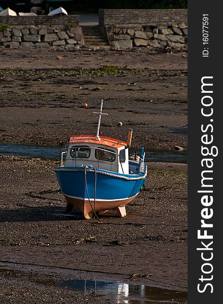 A small fishing boat stranded on the beach at low tide.