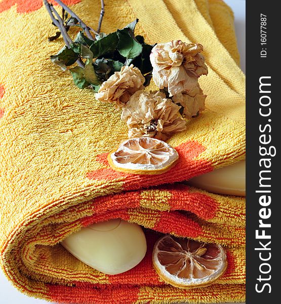 Terry, orange towel alongside yellow soap and lobules of dry lemon. Terry, orange towel alongside yellow soap and lobules of dry lemon