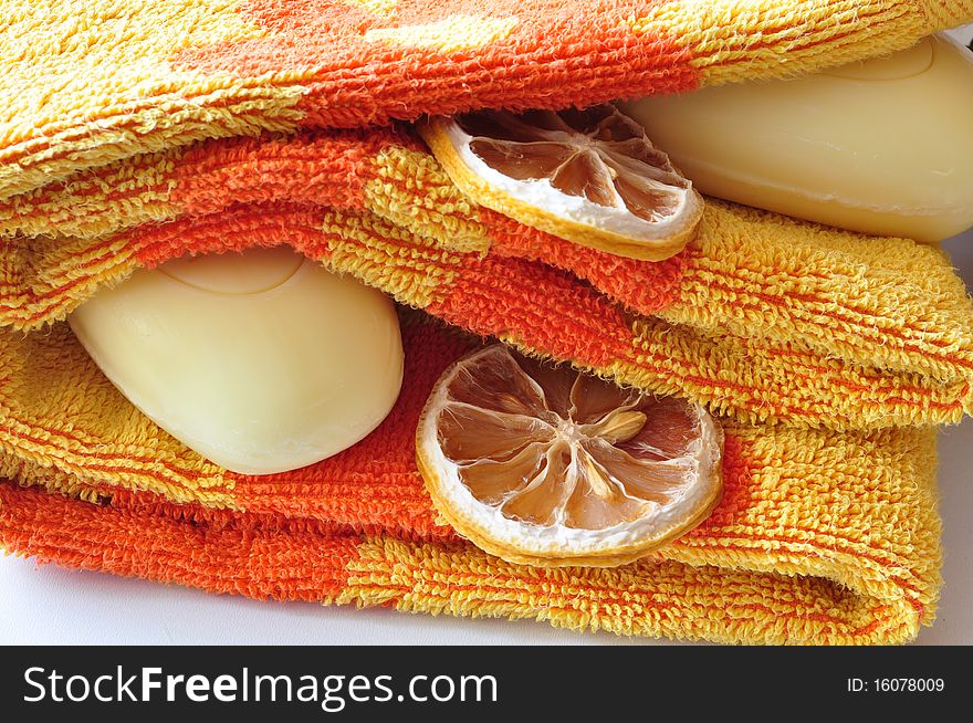 Terry, orange towel alongside yellow soap and lobules of dry lemon. Terry, orange towel alongside yellow soap and lobules of dry lemon