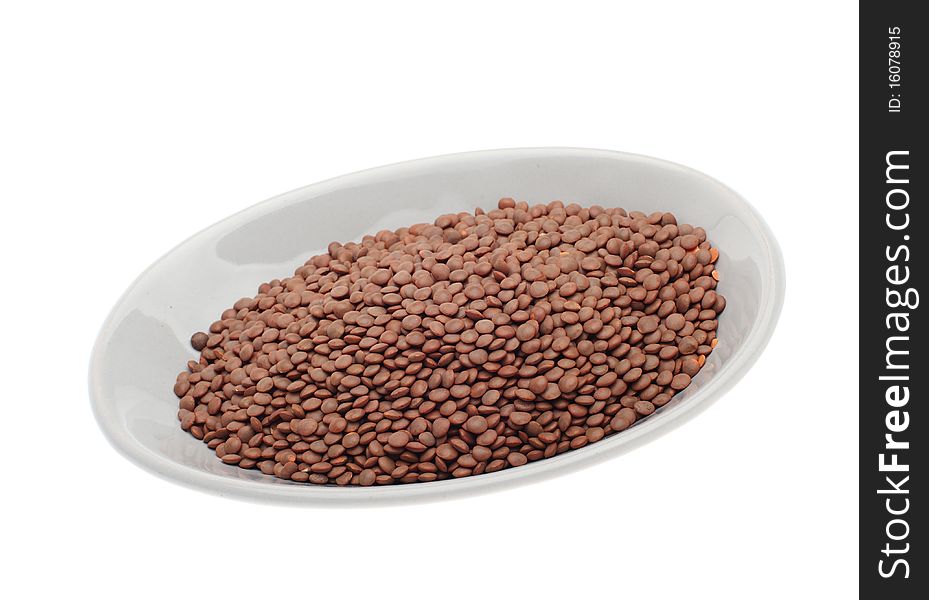 Brown uncooked lentils on plate isolated over white background