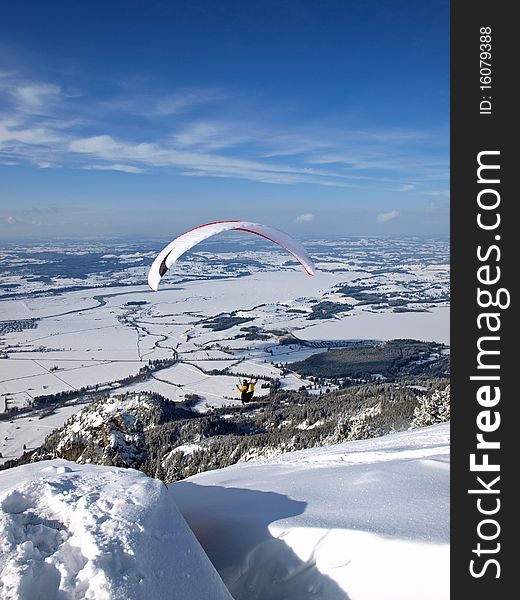 Paraglider flying from a mountain into a valley