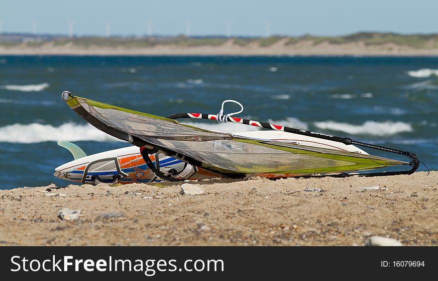 Windsurfboard with sail lying in the beach. Windsurfboard with sail lying in the beach