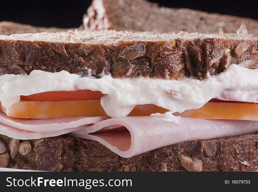 Close-up of sandwich with mayonnaise, turkey, and cheese.