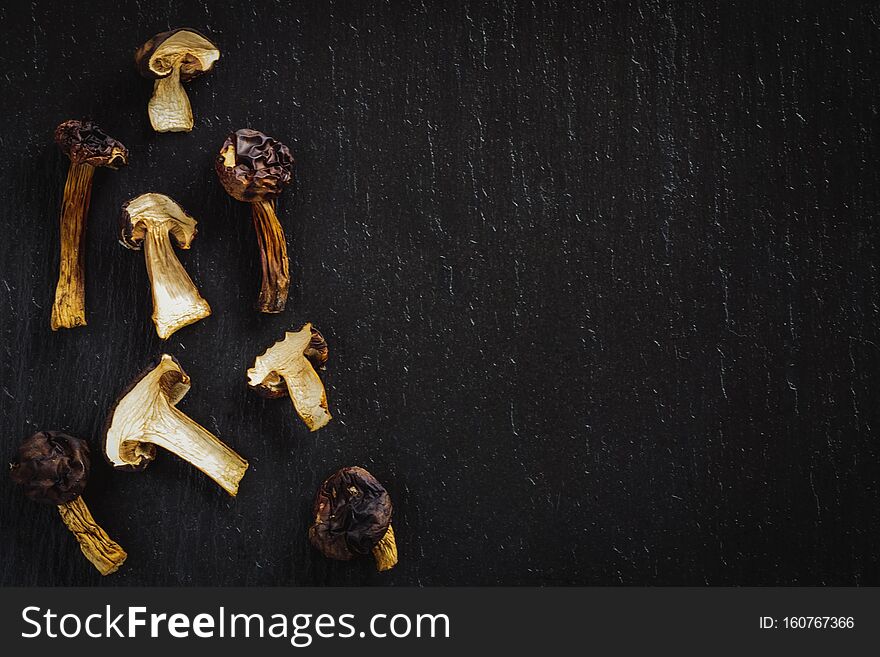 Dried slices of tasty mushrooms on black stone background.  Top view